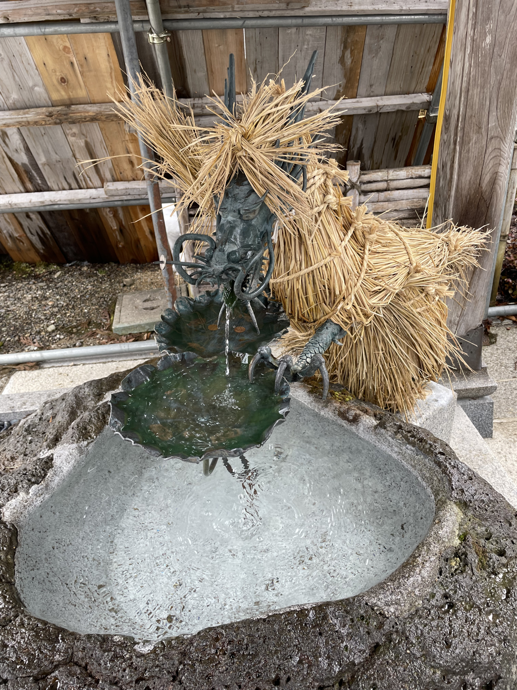 Dragon shaped water spout with snow in the background, wrapped in rice straw to insulate it against the winter cold and keep the water used for cleansing yourself flowing. 